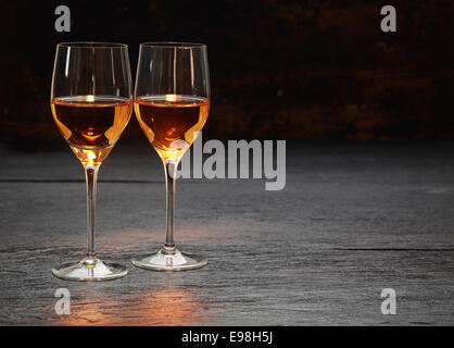 Pair of half-full half-empty wine glasses on stone surface Stock Photo