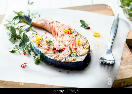 Cutlet of grilled gourmet salmon seasoned with fresh herbs and spices served on a wooden board in a seafood restaurant , low angle view Stock Photo