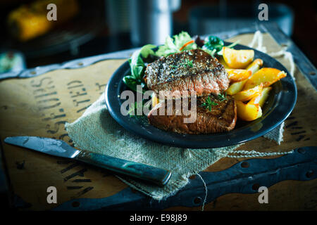 Succulent grilled beef steak and vegetables with roasted butternut and a fresh herb salad on a plate in a rustic setting on the Stock Photo