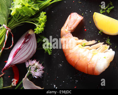 Single Shrimp Meat with Sliced lemon and Onion on Black Wooden Table Stock Photo