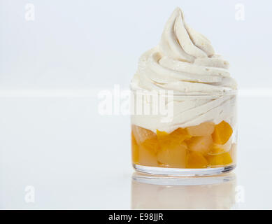 Fresh fruit salad topped with a swirl of healthy low-fat frozen yogurt served in a glass dish on white with copyspace Stock Photo