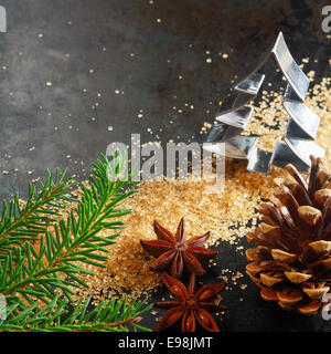 Christmas greeting card background with a cookie cutter in the shape of a Christmas tree with a pine branch, cone, caramelized brown sugar and star anise spice on a dark background with copyspace Stock Photo