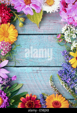 Beautiful fresh floral border of assorted colorful summer flowers on blue wooden boards with vertical copyspace Stock Photo