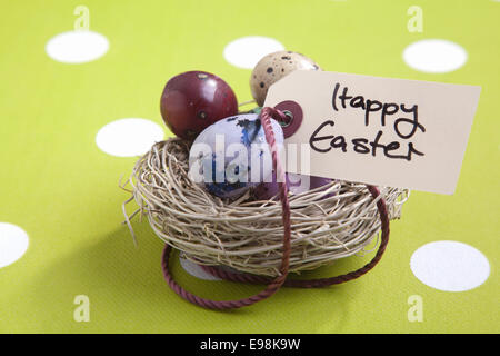 Colored eggs in a small nest with a Happy Easter tag Stock Photo