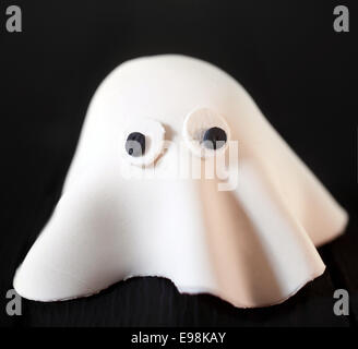 Cute scary white Halloween ghost made of pastry dough with large eyes on a black background symbolic of a traditional Halloween Stock Photo