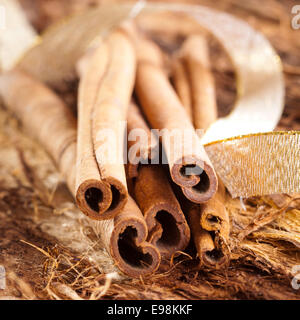 a few cinnamon sticks on wooden background an a golden bow Stock Photo