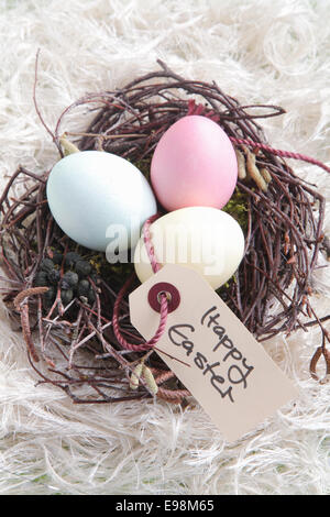 Three Easter Eggs in a nest with a handwritten Happy Easter sign Stock Photo