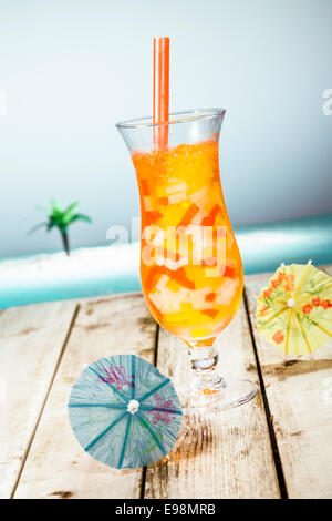 Mango Boba Cocktail Tea standing in front of a beach background with beautiful paper umbrellas. Stock Photo
