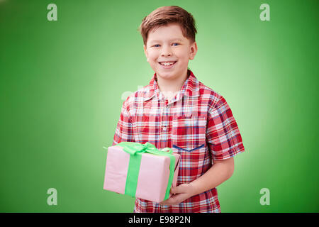 Cheerful kid with wrapped gift over green background Stock Photo