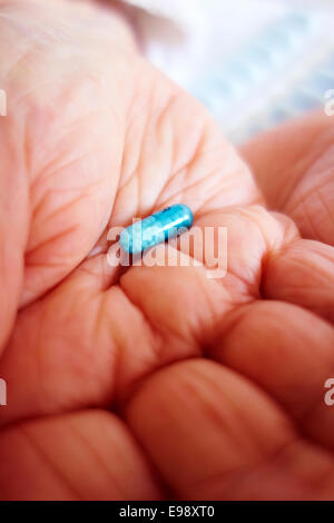 Senior person's hands holding a blue Bedranol propranolol hydrochloride pill / tablet /capsule prescription beta blocker medication - social care. Stock Photo