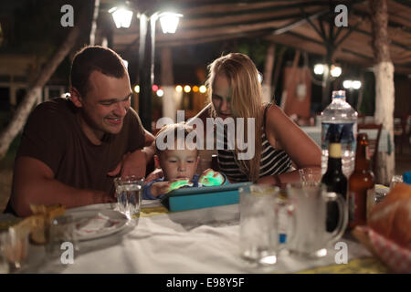 Parents and child with tablet PC in outdoor cafe Stock Photo