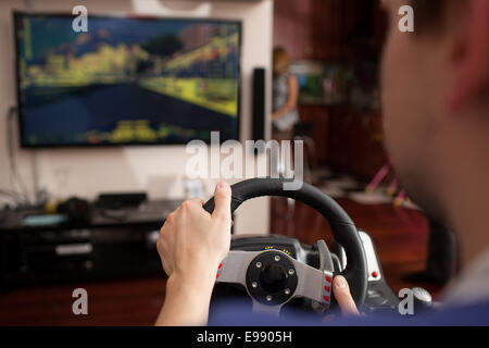 Man playing racing game with steering wheel simulator Stock Photo