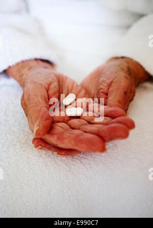 Senior person's hands holding medication - nursing home healthcare. Stock Photo