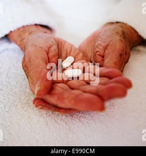 Senior person's hands holding white pill / tablet prescription medication - social care. Stock Photo