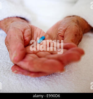 Senior person's hands holding a blue Bedranol propranolol hydrochloride pill / tablet /capsule prescription beta blocker medication - social care. Stock Photo