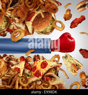 Fitness diet fight concept as a group of unhealthy junk food as hamburgers and fried fast foods being punched open by a person with a boxing glove as a symbol of fighting off cholesterol rich temptation. Stock Photo