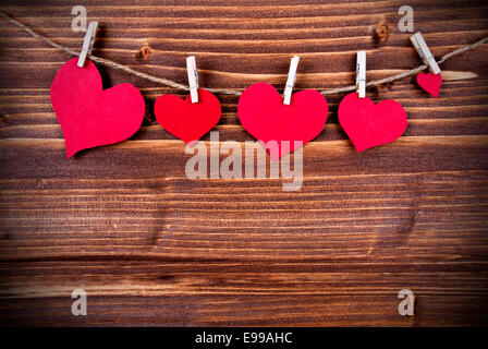 Many Red Hearts in different Sizes Hanging on a Line on Wooden Background with Copy Space Stock Photo