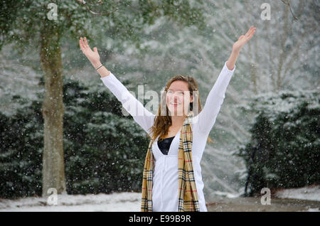 Let it Snow: A young woman raises her arms in victory of a beautiful Snow Shower. Stock Photo