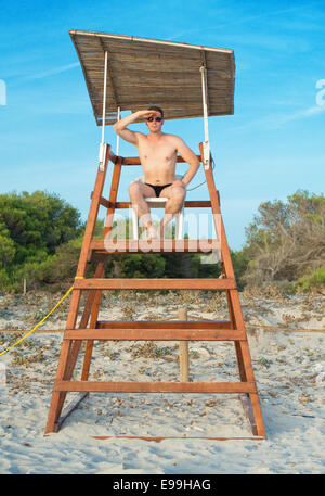 Man sitting on lifeguard tower on the beach. Stock Photo