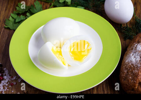 Two soft-boiled eggs in half on a plate, egg, parsley, spices and bread Stock Photo