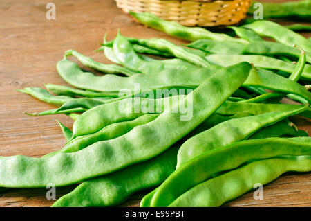 a pile of green bean pods on a wooden table Stock Photo