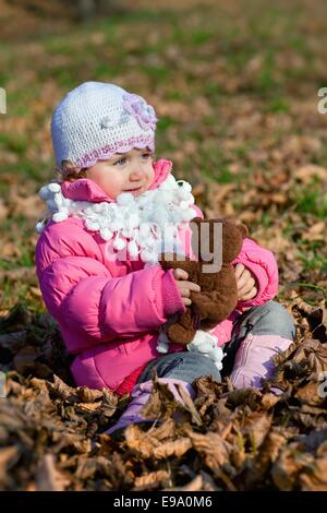 Happy girl with bear in park on autumn Stock Photo