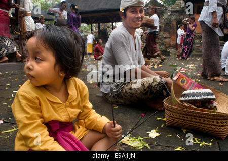 Several people pray and leave offerings in the Holy Monkey Forest during the celebration of Galungan. Galungan festival, the most important of Bali, symbolizes the victory of Drama (virtue) over Adharma (evil). During the days that last Balinese parade celebrations across the island adorned with long bamboo sticks (penjor) decorated with ears of corn, coconut, rice cakes and cupcakes as well as white or yellow fabrics, fruits flowers. This festival is celebrated every 210 days. Ubud. Bali. Stock Photo