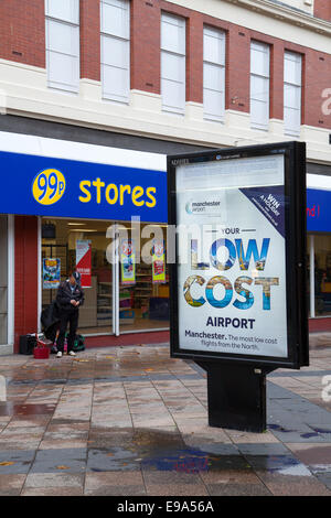 Low Cost Travel Poster, and Ninety Nine pence Stores in Town Centre as Warrington Borough Council propose to regenerate the Bridge Street Quarter.  The proposed development will transform the  in Bridge Street area into a vibrant new commercial part of the town centre providing a new market hall, cinema, restaurants, offices and a new public square. The existing shopping centre has seen a significant decline in trade over recent years. Stock Photo