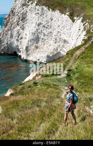 A young female hiker walks The South West Coastal Path, Dorset. Part of The Jurassic Coastline of England. Stock Photo