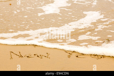 Happy new year written in sand on beach Stock Photo