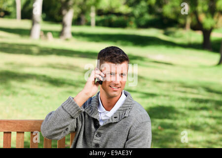 Young man phoning on the bench Stock Photo