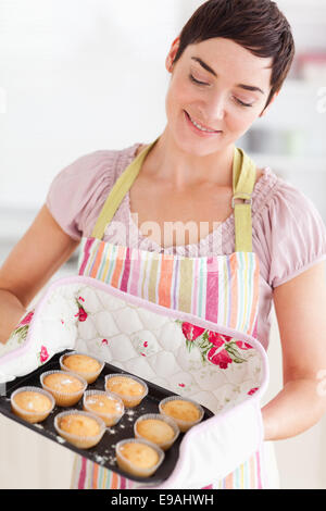 Happy brunette woman showing muffins Stock Photo