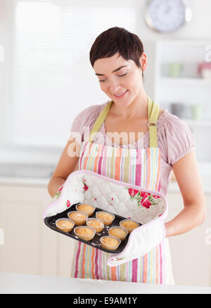 Smiling brunette woman showing muffins Stock Photo