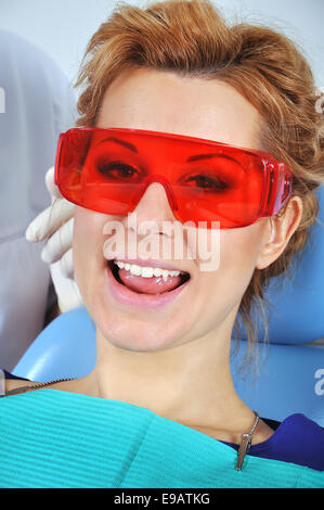 happy girl sitting in a dental chair in red glasses Stock Photo