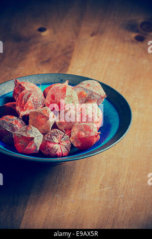 Physalis alkekengi. Drying Chinese lantern flower seed casing in a bowl on a wooden table. Vintage filter applied Stock Photo