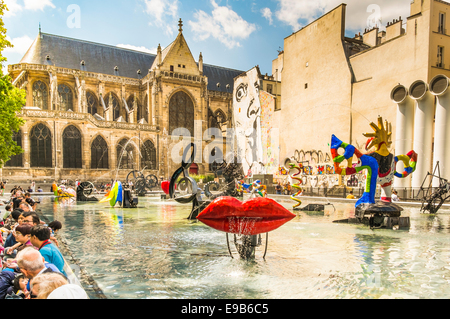 tourists taking a break at  the stravinsky fountain close to the centre georges pompidou,  in the background saint merry church Stock Photo