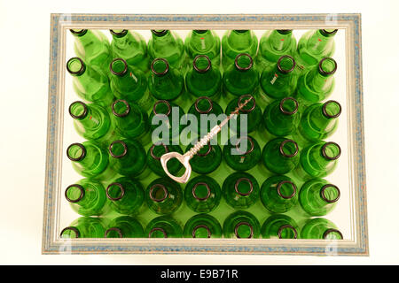 Rows of empty Heineken bottles inside of a frame with a bottle opener on top Stock Photo