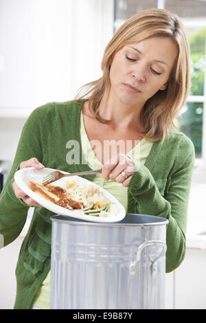 Woman Scraping Food Leftovers Into Garbage Bin Stock Photo