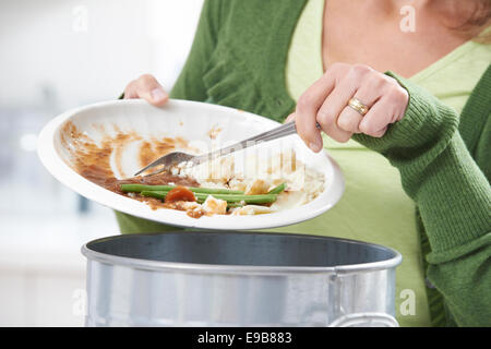 Woman Scraping Food Leftovers Into Garbage Bin Stock Photo