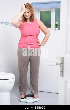 Overweight Woman Weighing Herself On Scales In Bathroom Stock Photo