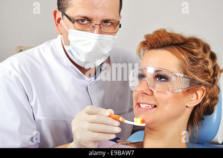 Dentist shows a patient how to brush teeth Stock Photo