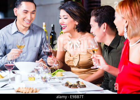 Asian friends, two couples, dining in fancy restaurant eating good food and drinking wine Stock Photo