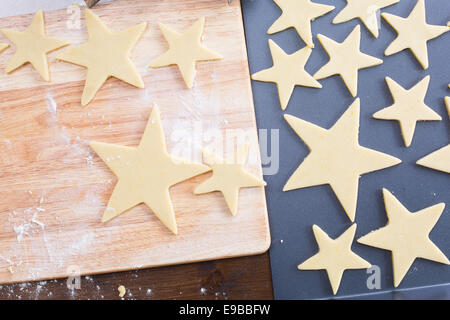 Star shaped Christmas cookie dough on cutting board and baking sheet, from above. Stock Photo