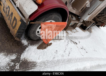 peterbilt 379 Semi trailer with a flatdeck oversize load of huge giant large mining tyres with warning flags snow and ice covered in pullout winter Stock Photo