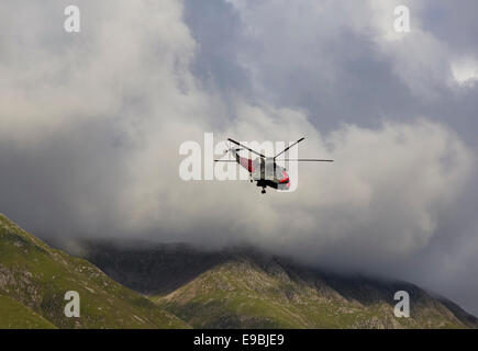 Royal Navy rescue helicopter operating above the slopes of Glen Nevis near Ben Nevis, Scotland Stock Photo