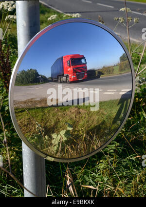 lorry passing warning sign of sharp bend and circular safety mirror to give drivers emerging from junction view of road uk Stock Photo