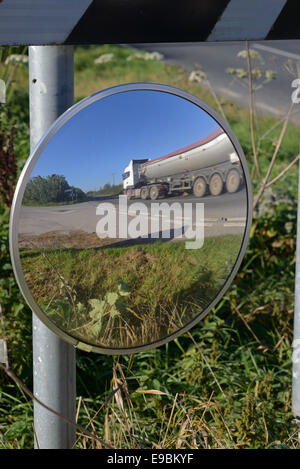 lorry passing warning sign of sharp bend and circular safety mirror to give drivers emerging from junction view of road uk Stock Photo