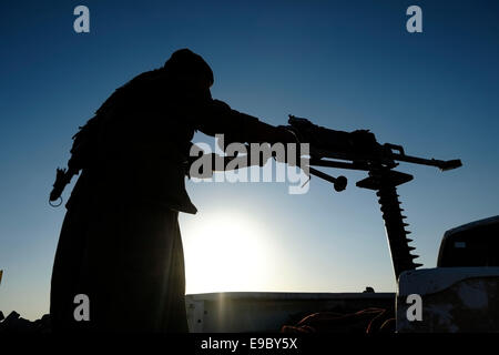 A Kurdish fighter of the People's Defense Forces HPG the military wing of the Kurdistan Workers' Party PKK with a DShK heavy machine gun mounted on an open-backed civilian pickup truck patrolling in Makhmur area near Mosul in northern Iraq Stock Photo