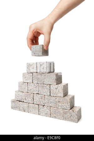 Man building pyramid made of small blocks of granite rock. Stock Photo