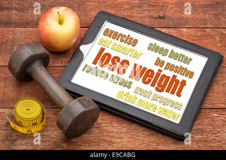 lose weight - tips on a digital tablet with a dumbbell, apple and tape measure Stock Photo